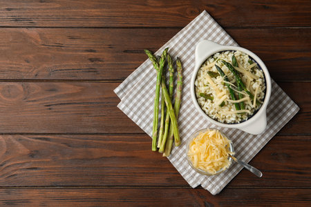 Delicious risotto with asparagus served on wooden table, flat lay. Space for textの写真素材