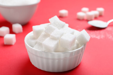 Refined sugar cubes in bowl on red backgroundの写真素材