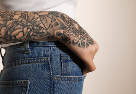 Woman with tattoos on arm against light background, closeupの写真素材