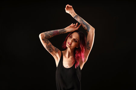 Beautiful woman with tattoos on arms against black backgroundの写真素材