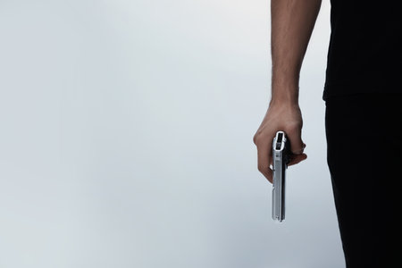 Professional killer with gun on white background, closeupの写真素材