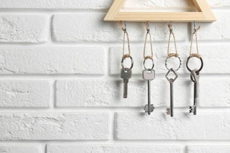 Wooden key holder on white brick wall indoors, closeup. Space for textの写真素材