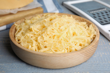 Tasty grated cheese on light gray wooden table