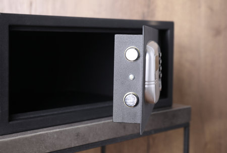 Black steel safe with electronic lock on gray table, closeup