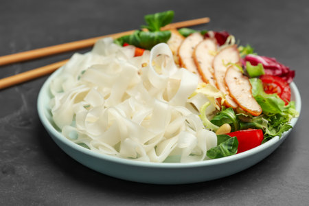 Tasty cooked rice noodles with chicken and vegetables on black tableの写真素材