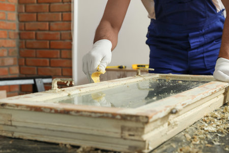 Man repairing old damaged window at table indoors, closeupの写真素材