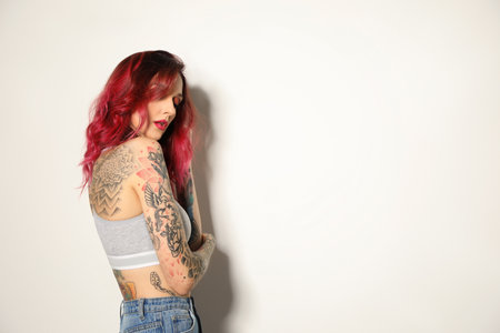 Beautiful woman with tattoos on body against white background. Space for textの写真素材