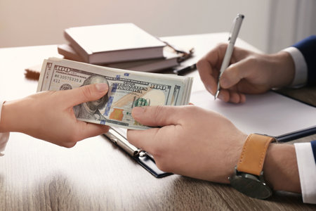 Woman giving bribe to man at table in office, closeup