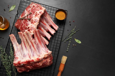 Raw ribs with thyme and pepper on black table, flat layの写真素材