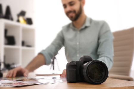 Professional photographer working at table in office, focus on cameraの写真素材