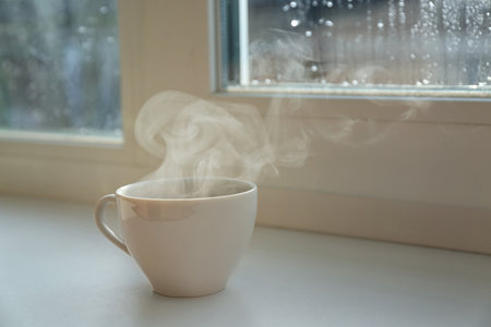 Cup of hot drink near window on rainy day. Space for textの写真素材