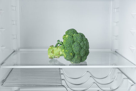Fresh organic broccoli on empty shelf in fridgeの写真素材