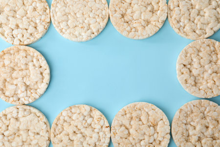 Frame made of puffed rice cakes on light blue background, flat lay. Space for textの写真素材