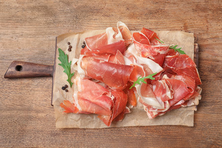 Pile of tasty prosciutto on wooden table, top viewの写真素材