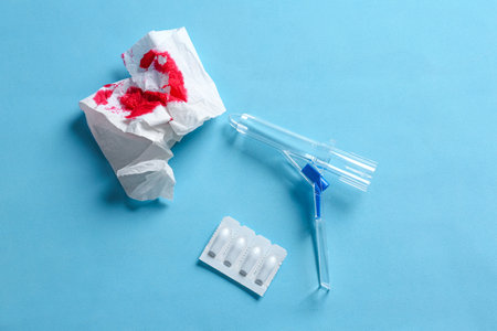 Anoscope, suppositories and toilet paper with blood on light blue background, flat lay. Hemorrhoid treatmentの写真素材