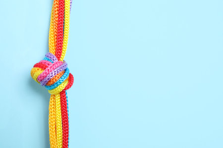 Top view of colorful ropes tied together on light blue background, space for text. unity conceptの写真素材