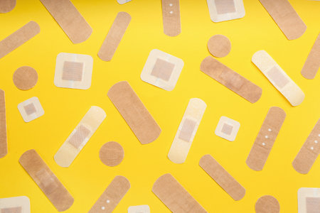 Different types of sticking plasters on yellow background, flat layの写真素材