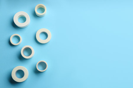 Sticking plaster rolls on light blue background, flat lay. Space for textの写真素材