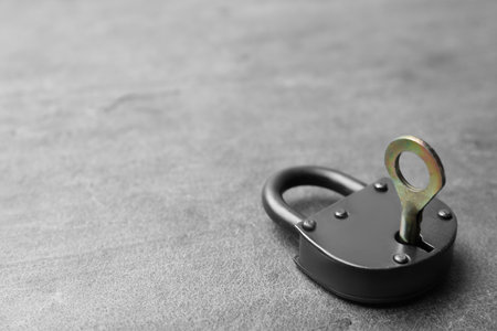 Steel padlock with key on gray background, space for text. safety concept