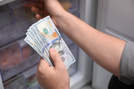 Man hiding money in refrigerator, closeup. financial savingsの写真素材