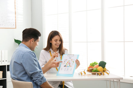 Young nutritionist consulting patient at table in clinicの写真素材