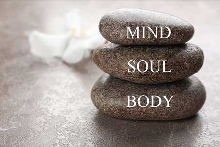 Stones with words MIND, BODY, SOUL on brown marble background, space for text. Zen lifestyleの写真素材