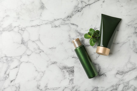 Cosmetic products and mint on white marble table, flat lay. Space for textの写真素材