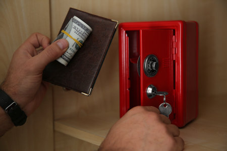 Man putting passport and money into small steel safe, closeupの写真素材