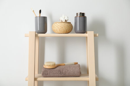 Wooden shelving unit with toiletries near white wall indoors. bathroom interior elementsの写真素材