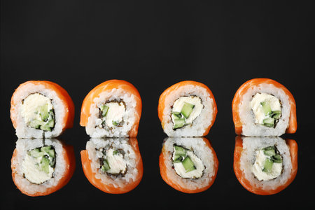 Delicious sushi rolls on black mirror surfaceの写真素材