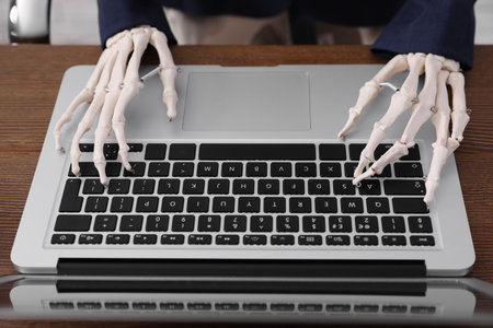 Human skeleton in suit using laptop at table, closeupの写真素材