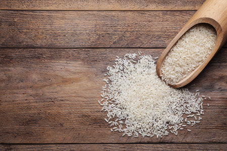 Uncooked rice and scoop on wooden table, top view. Space for textの写真素材