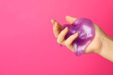 Woman playing with purple slime on pink background, closeup. antistress toyの写真素材