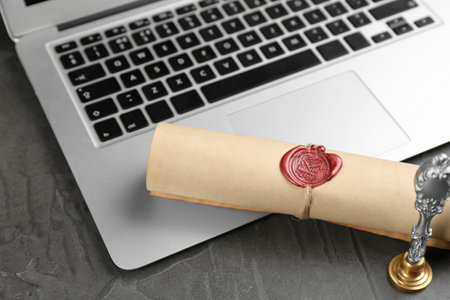 Notary's public pen and sealed document near laptop on gray stone tableの写真素材