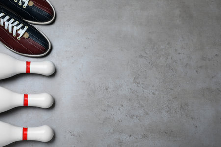 Bowling shoes and pins on gray stone table, flat lay. Space for textの写真素材