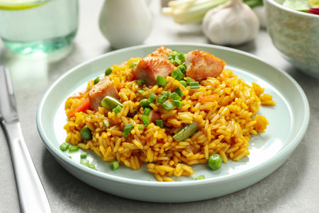 Delicious rice pilaf with vegetables and chicken on light gray tableの写真素材
