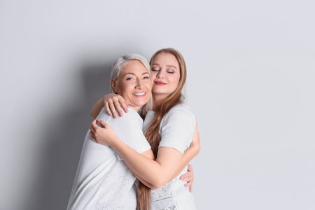 Mother and her adult daughter on white background. Space for textの写真素材