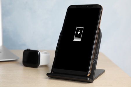 Mobile phone charging with wireless pad on wooden table, closeup