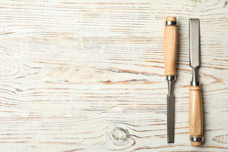 Chisels on white wooden background, flat lay with space for text. Carpenter's toolsの写真素材