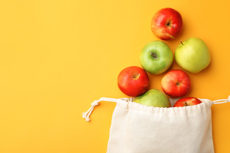 Cotton eco bag and apples on yellow background, flat lay. Space for textの写真素材