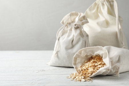 Cotton eco bags with oat flakes on white wooden table. Space for textの写真素材