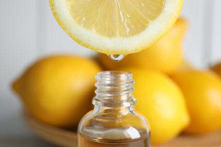 Citrus essential oil dripping from lemon slice into bottle, closeupの写真素材