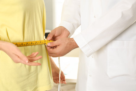 Nutritionist measuring patient's waist in clinic, closeupの写真素材