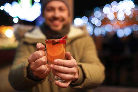Happy man with mulled wine at winter fair, focus on handsの写真素材