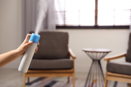 Woman spraying air freshener at home, closeup