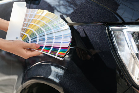 Woman with palette samples choosing color for painting car, closeupの写真素材
