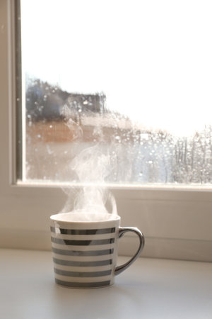 Cup of hot drink near window on rainy day. Space for textの写真素材