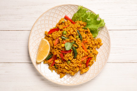 Delicious rice pilaf with vegetables on white wooden table, top view