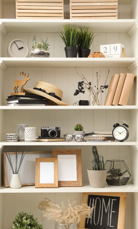 White shelving unit with photo frames and different decorative elementsの写真素材