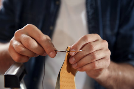 Man sewing piece of leather in workshop, closeupの写真素材